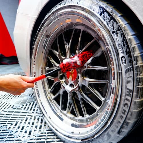 Person cleaning car wheel with a brush