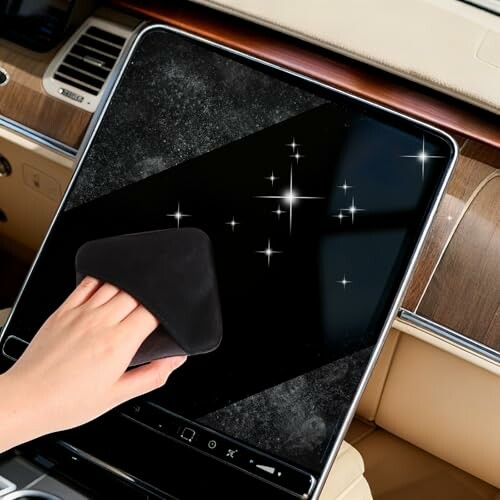 Hand cleaning a car touchscreen with a cloth.