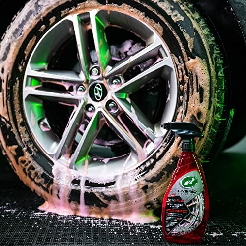 Car tire being cleaned with a red spray bottle.