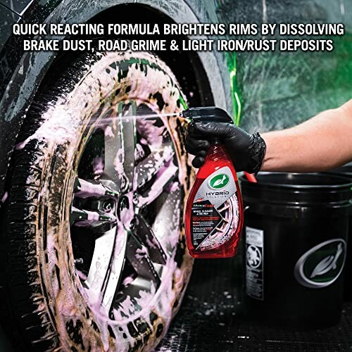 Person cleaning car wheel with spray to remove brake dust and grime.